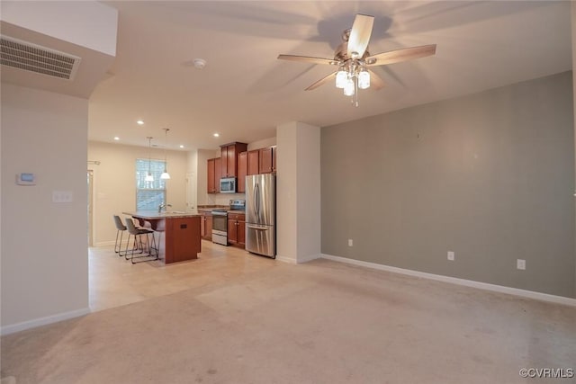 kitchen featuring brown cabinets, stainless steel appliances, visible vents, light carpet, and a kitchen bar