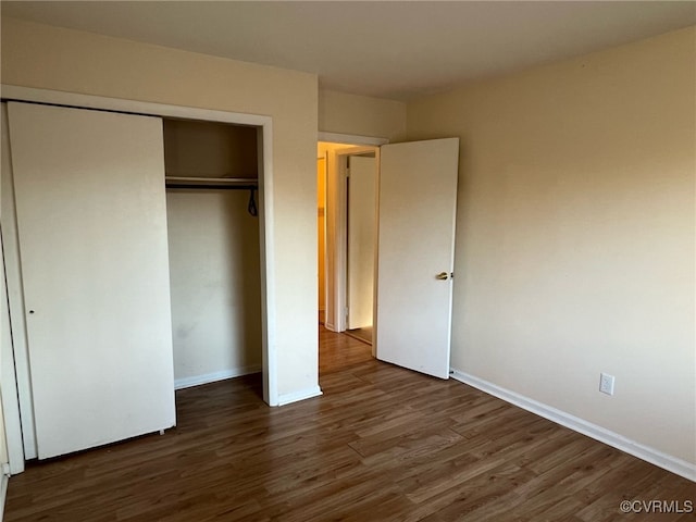 unfurnished bedroom with a closet, wood finished floors, and baseboards