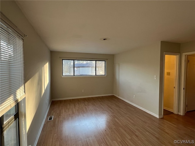 spare room featuring visible vents, baseboards, and wood finished floors