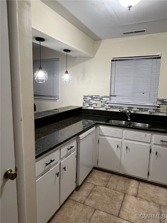 kitchen with visible vents, dark countertops, a sink, white dishwasher, and backsplash