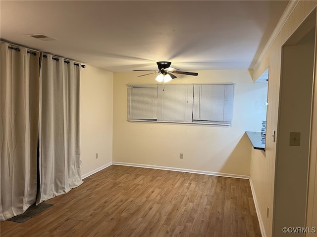 spare room featuring a ceiling fan, baseboards, and wood finished floors