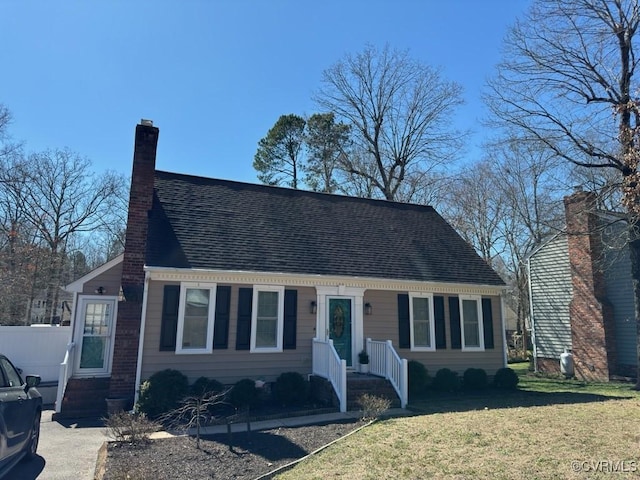 view of front of property with a shingled roof, a front yard, fence, and a chimney