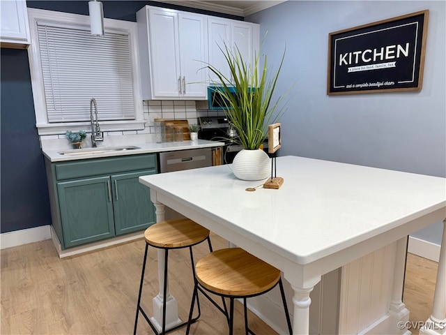 kitchen with light wood finished floors, light countertops, decorative backsplash, a sink, and a kitchen breakfast bar