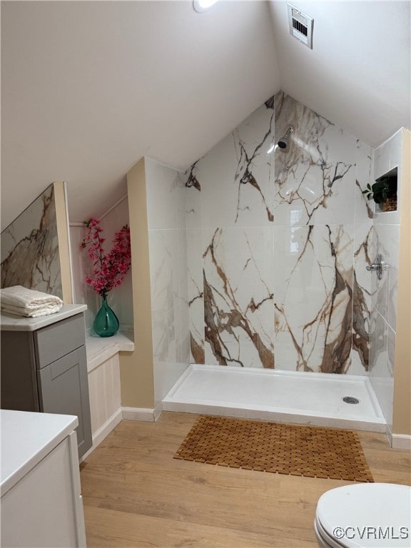 bathroom with toilet, a marble finish shower, and wood finished floors