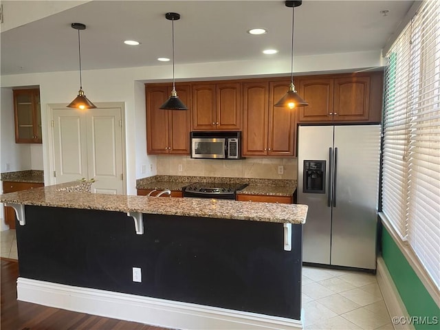 kitchen with stone counters, a breakfast bar area, stainless steel appliances, and recessed lighting