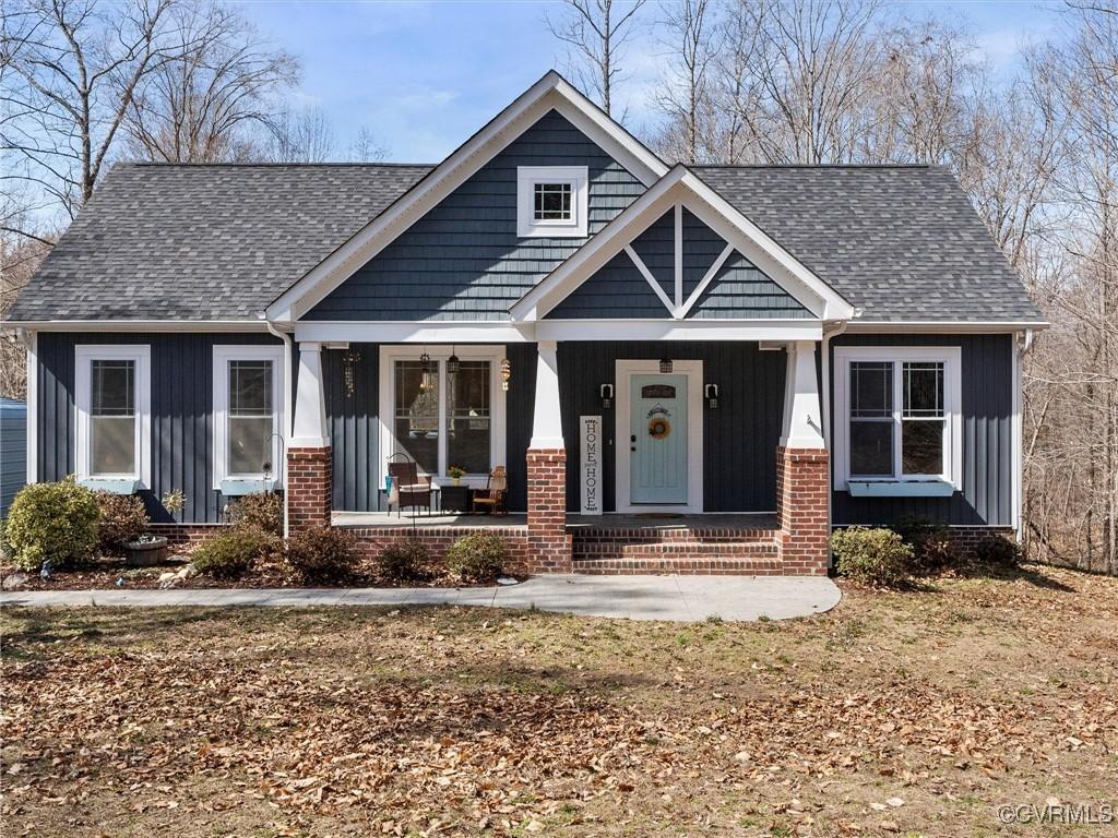 craftsman-style house with brick siding, covered porch, board and batten siding, and a shingled roof