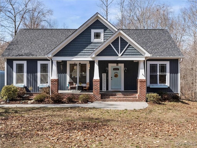 craftsman-style house with brick siding, covered porch, board and batten siding, and a shingled roof