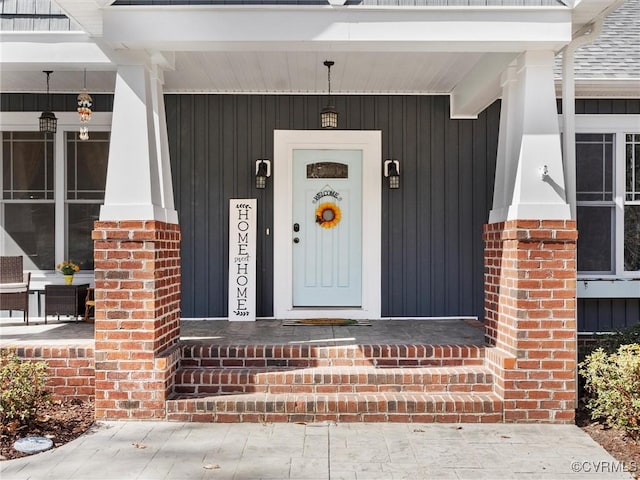 doorway to property with brick siding and covered porch