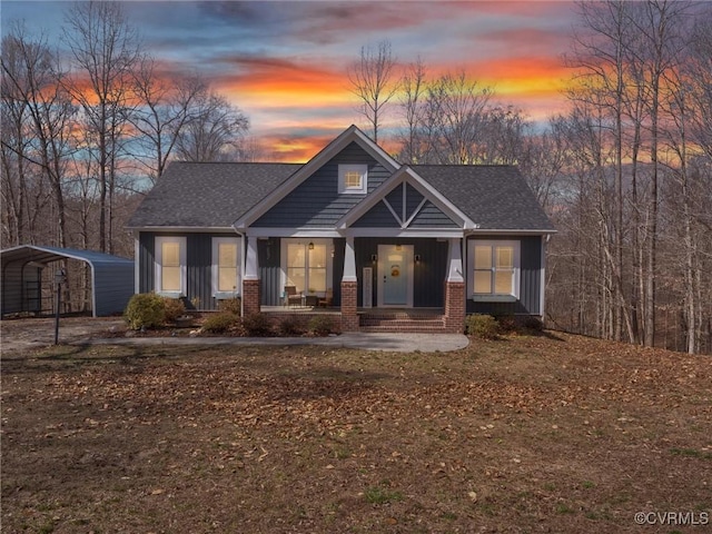 craftsman-style house with brick siding, a detached carport, covered porch, and a shingled roof