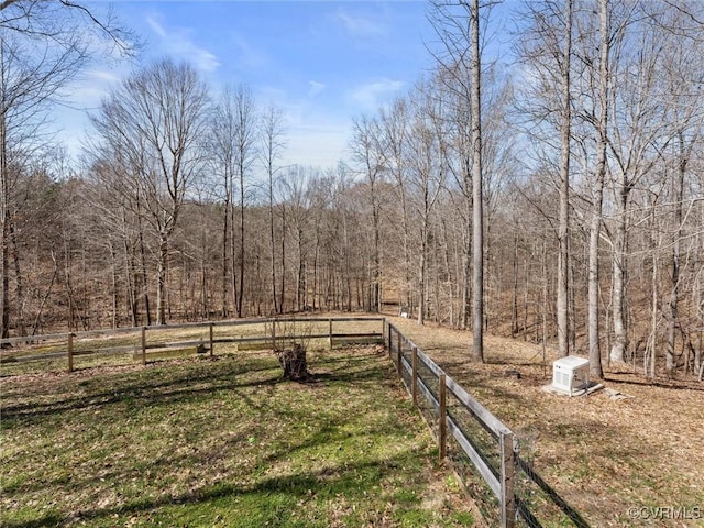 view of yard featuring a forest view and fence