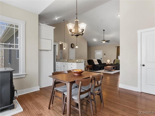 dining area featuring baseboards, high vaulted ceiling, wood finished floors, and ceiling fan with notable chandelier