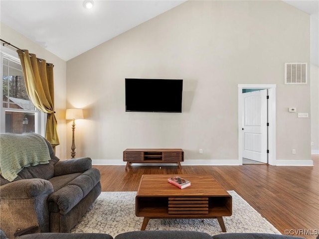 living room with visible vents, baseboards, high vaulted ceiling, and wood finished floors