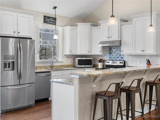 kitchen featuring under cabinet range hood, a breakfast bar, white cabinets, stainless steel appliances, and a sink