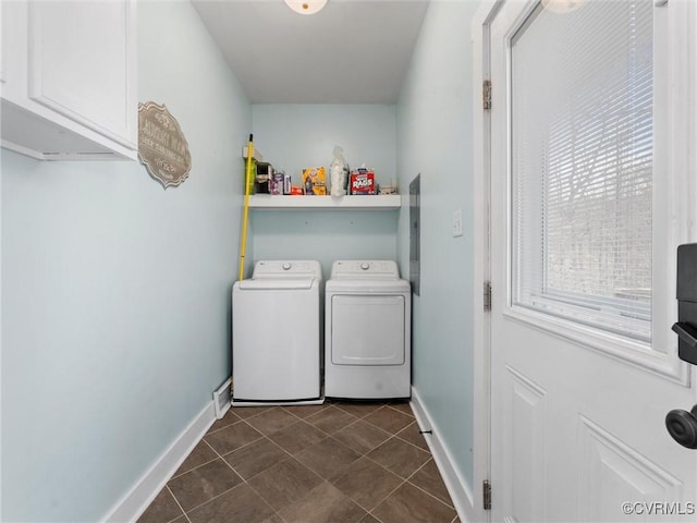 laundry room with dark tile patterned floors, baseboards, washing machine and dryer, and cabinet space