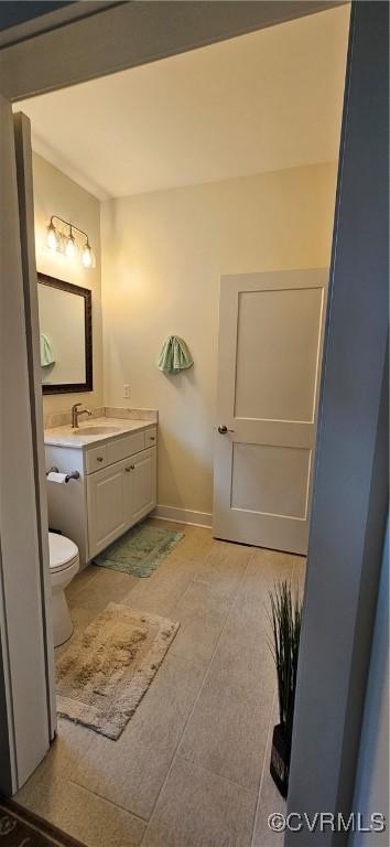 bathroom featuring baseboards, toilet, vanity, and tile patterned flooring