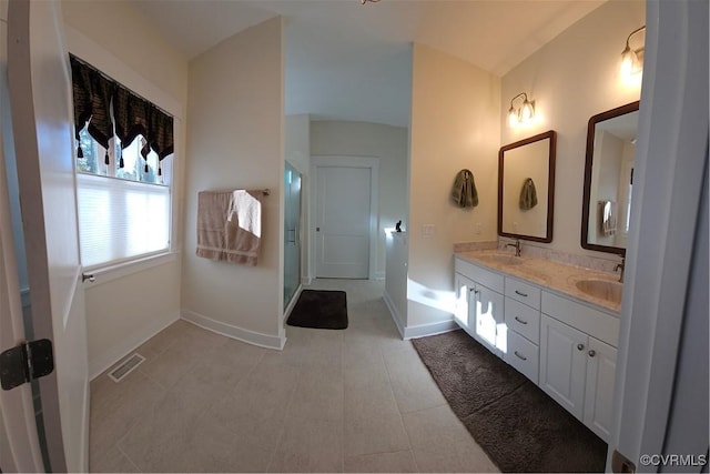 full bath with visible vents, a sink, a shower stall, double vanity, and baseboards