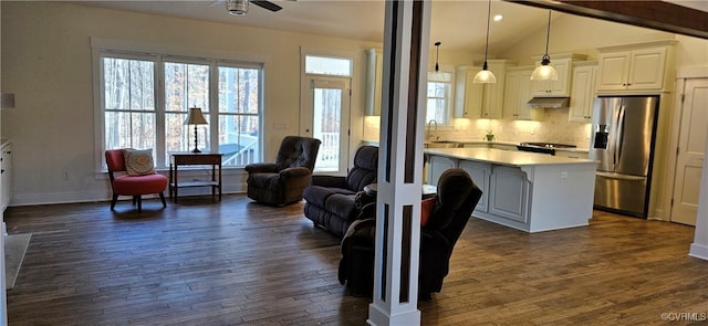 kitchen with a kitchen island, stainless steel fridge with ice dispenser, under cabinet range hood, open floor plan, and a sink