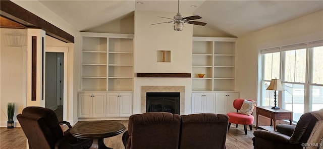 living area featuring a ceiling fan, wood finished floors, a fireplace, and vaulted ceiling