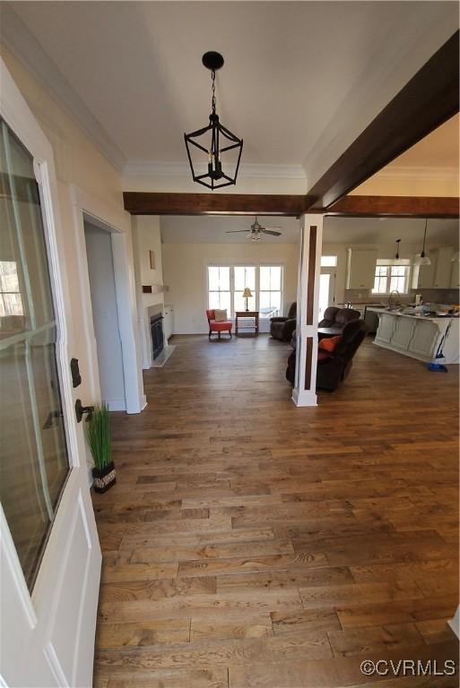 hallway with an inviting chandelier, crown molding, and wood finished floors