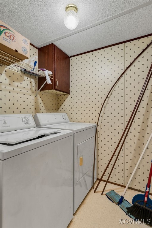 laundry area with a textured ceiling, cabinet space, light floors, and washing machine and clothes dryer