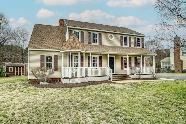 view of front of house with a porch, a chimney, an outdoor structure, and a front lawn