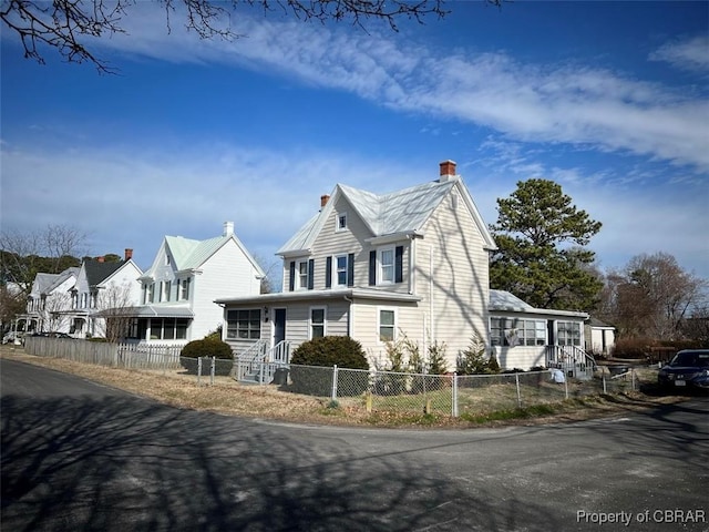 view of front facade with a fenced front yard and a chimney