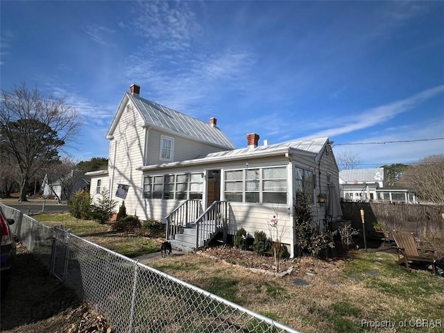 traditional-style home with a fenced backyard, metal roof, and a chimney