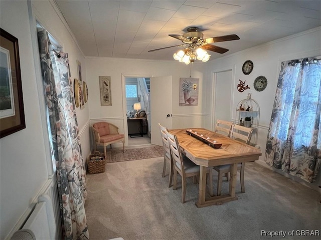 carpeted dining room featuring ornamental molding and a ceiling fan