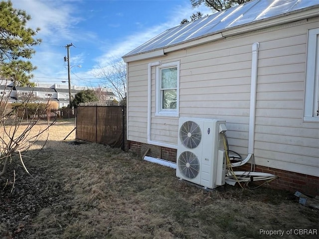 exterior space with ac unit, fence, and metal roof