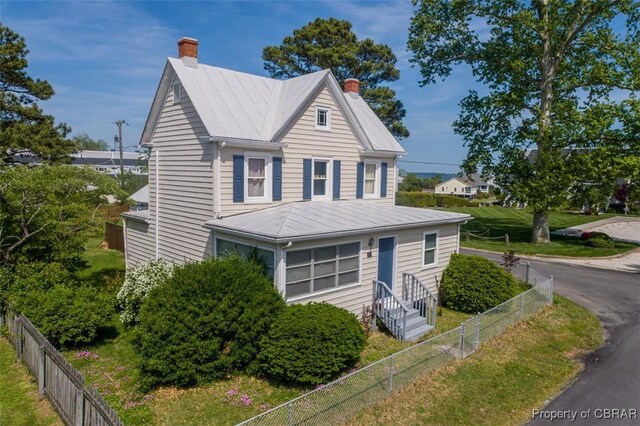 111 Taylor Ave, Urbanna, VA 23175 - traditional home with a standing seam roof, a chimney, metal roof, and a fenced backyard