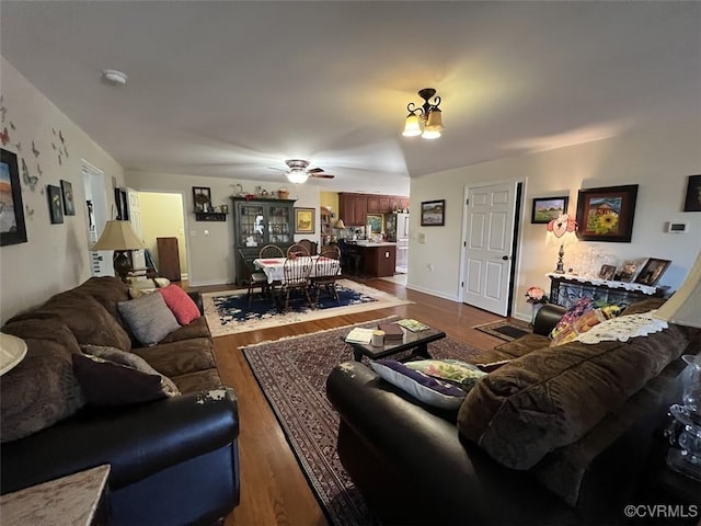 living area featuring dark wood finished floors, baseboards, and ceiling fan