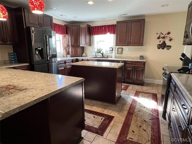 kitchen featuring a sink, baseboards, light countertops, appliances with stainless steel finishes, and a center island