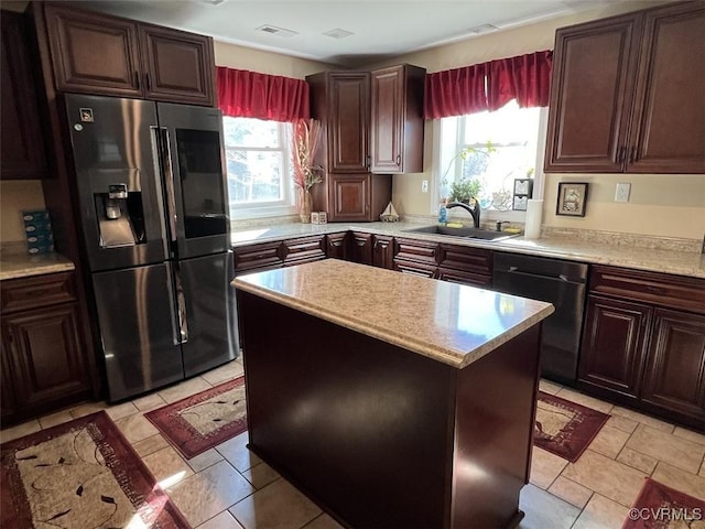 kitchen with light countertops, appliances with stainless steel finishes, a sink, dark brown cabinetry, and a kitchen island