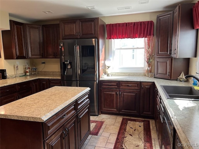 kitchen featuring a kitchen island, a sink, visible vents, light countertops, and fridge with ice dispenser