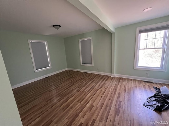 spare room with baseboards and wood finished floors