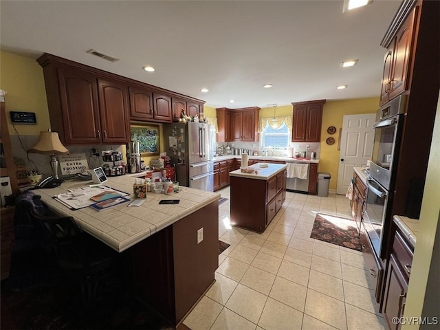 kitchen featuring light tile patterned flooring, recessed lighting, a peninsula, visible vents, and appliances with stainless steel finishes