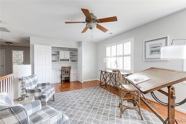 office featuring a ceiling fan, baseboards, visible vents, and light wood finished floors