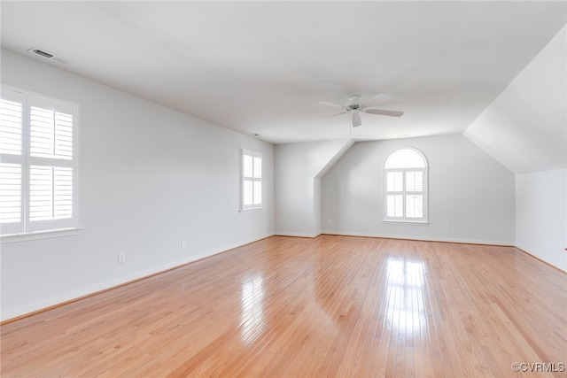 bonus room with light wood-type flooring, ceiling fan, visible vents, and baseboards