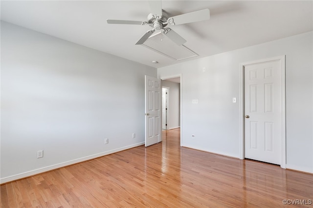 unfurnished bedroom featuring attic access, light wood-type flooring, ceiling fan, and baseboards