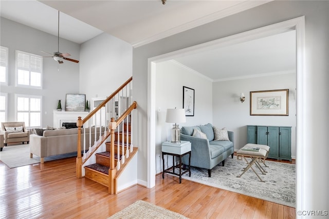 living area featuring a fireplace, baseboards, stairs, ornamental molding, and wood-type flooring