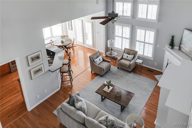 living area with a towering ceiling and wood finished floors