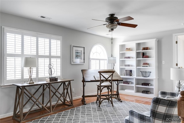 office space with baseboards, ceiling fan, visible vents, and wood finished floors