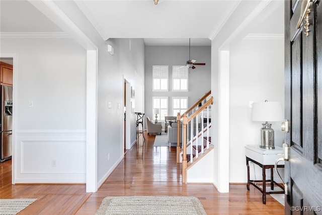 foyer with light wood-style floors, stairs, and ornamental molding