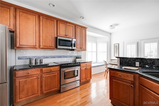 kitchen with appliances with stainless steel finishes, brown cabinets, and backsplash