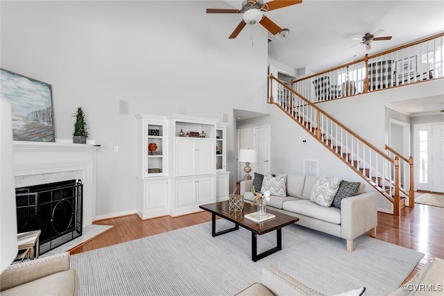 living room featuring ceiling fan, stairway, a fireplace, and wood finished floors