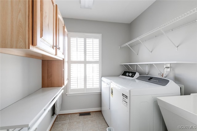 washroom with washing machine and clothes dryer, cabinet space, light tile patterned flooring, a sink, and baseboards