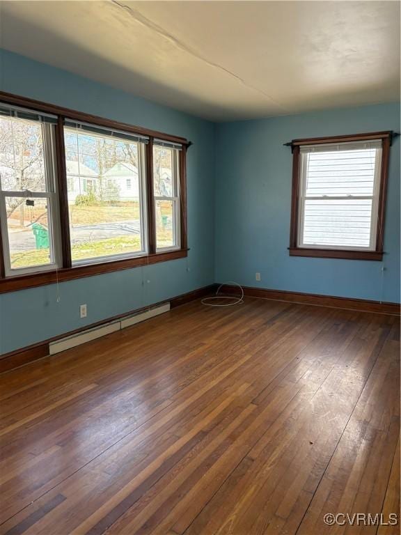 unfurnished room with hardwood / wood-style floors, baseboard heating, and baseboards