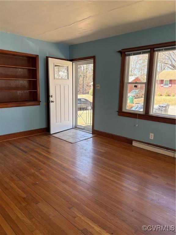 interior space featuring a baseboard radiator, baseboards, and wood finished floors