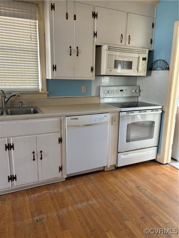 kitchen featuring light wood-type flooring, white appliances, white cabinets, and a sink