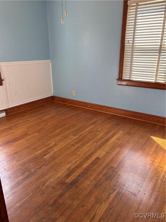 empty room with wood-type flooring and baseboards